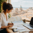 Traveler organizing maps, notes, passport, and laptop at a cafe table