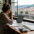 Traveler planning a complex trip with a laptop, map, notebook, and tickets on a cafe table