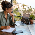 Traveler comparing digital and paper trip-planning materials at a cafe table